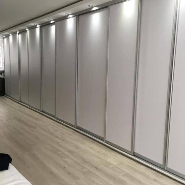 Luxe schuifwandkast over volledige muur met ingebouwde spotverlichting